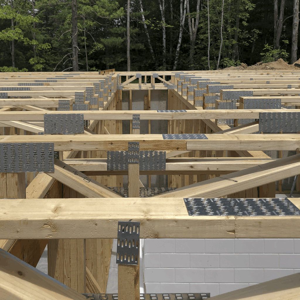 Structural framing stage of a residential addition in Michigan showing wooden joists, metal connectors, and foundation walls